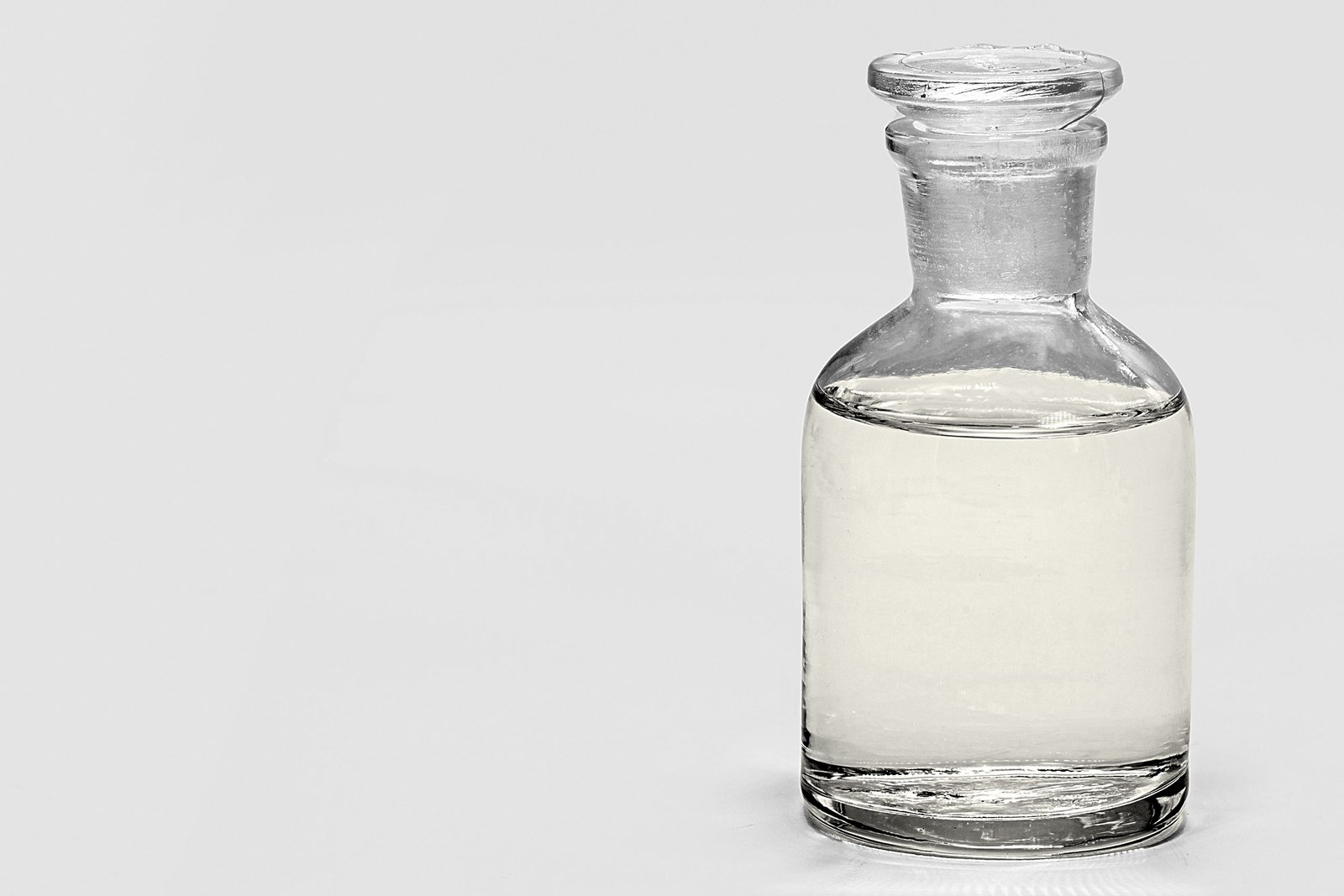 Clear liquid alkyl benzene in industrial glass flask with laboratory equipment